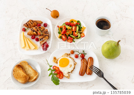 Fried egg and grilled sausages served with fresh tomatoes, sliced bell pepper, cucumbers. Fried egg and grilled sausages served with fresh tomatoes, sliced bell pepper, cucumbers. 135785039