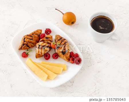 Croissants. sliced cheese and raspberries with a cup of coffee. 135785043