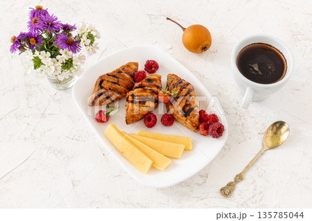 Croissants. sliced cheese and raspberries with a cup of coffee. 135785044