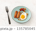 Fried egg and grilled sausages served with fresh tomatoes on the plate. 135785045