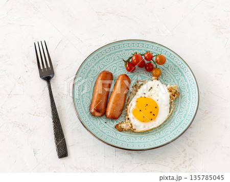Fried egg and grilled sausages served with fresh tomatoes on the plate. 135785045
