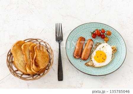 Fried egg and grilled sausages served with fresh tomatoes on the plate. 135785046