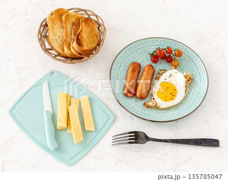 Fried egg and grilled sausages served with fresh tomatoes on the plate. 135785047