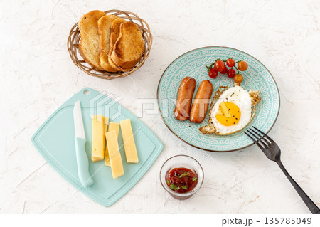 Fried egg and grilled sausages served with fresh tomatoes on the plate. 135785049