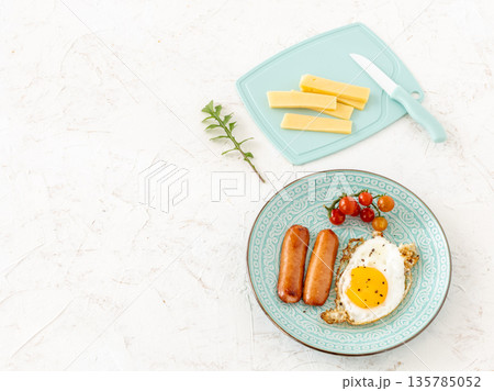 Fried egg and grilled sausages served with fresh tomatoes on the plate. 135785052