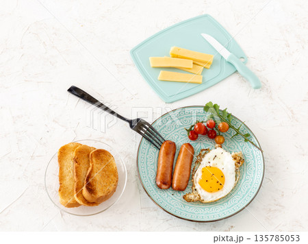 Fried egg and grilled sausages served with fresh tomatoes on the plate. 135785053