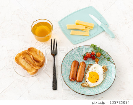 Fried egg and grilled sausages with a cup of tea. 135785054