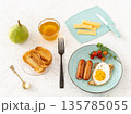 Fried egg and grilled sausages with a cup of tea. 135785055