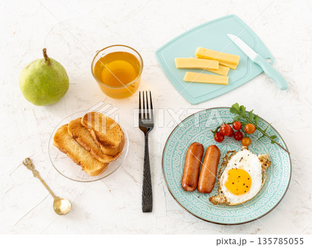 Fried egg and grilled sausages with a cup of tea. 135785055