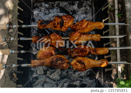 Chicken shanks on skewers on grill, grilling. 135785851