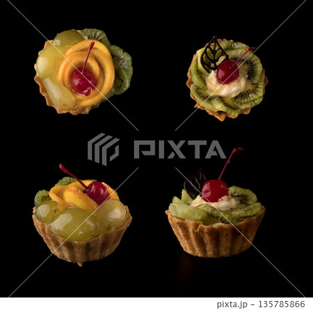 Fruit dessert cake with cherries, shekolad, grapes sponges, kiwi slices and orange slices on a black background isolated, collage Fruit dessert cake with cherries, shekolad, grapes sponges, kiwi slices and orange slices on a black background isolated, collage 135785866