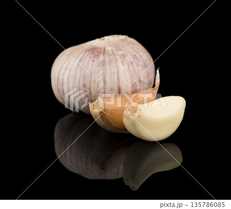 garlic, peeled and in the husk, on a black background with reflection 135786085