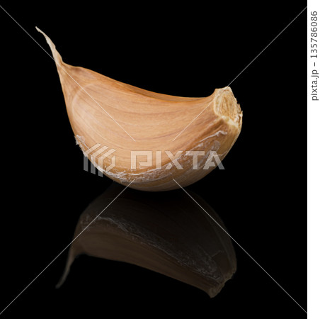 a clove of garlic in the husk, on a black background, with reflection a clove of garlic in the husk, on a black background, with reflection 135786086
