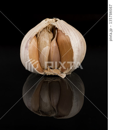 garlic in the husk, on a black background, with reflection 135786087