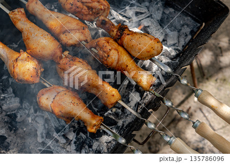 Chicken shanks on skewers on grill, grilling. 135786096