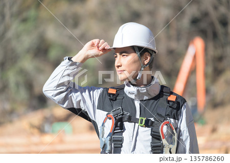 工事現場でヘルメットを被る日本人男性 工事現場でヘルメットを被る日本人男性 135786260