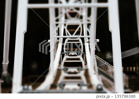 A low-angle, abstract shot from inside a Ferris wheel structure, creating an immersive, architectural view. The steel framework A low-angle, abstract shot from inside a Ferris wheel structure, creating an immersive, architectural view. The steel framework 135786380