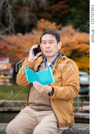 秋の公園でスマホを使う男性 秋の公園でスマホを使う男性 135787861