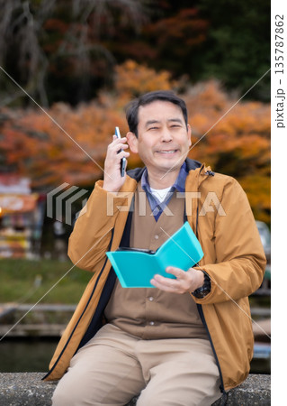 秋の公園でスマホを使う男性 秋の公園でスマホを使う男性 135787862