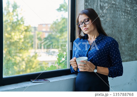 Mature tired, stressed businesswoman standing near window 135788768