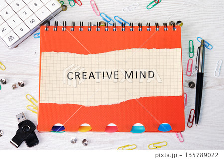An open notebook featuring Creative mind text on a grid page rests on a desk An open notebook featuring Creative mind text on a grid page rests on a desk 135789022