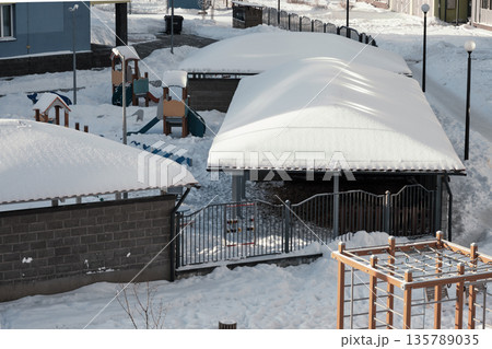 Residential outdoor space in winter shows a colorful childrens playground equipment partially buried under fresh snow Residential outdoor space in winter shows a colorful childrens playground equipment partially buried under fresh snow 135789035