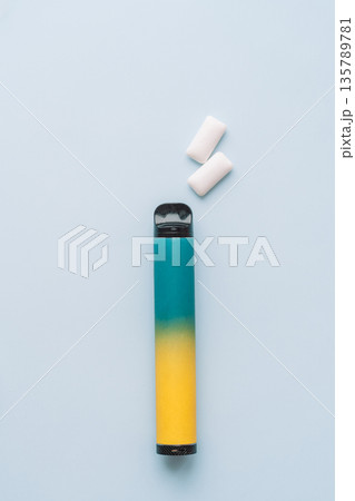 Disposable vape pen with chewing gum sticks on blue background, top view Disposable vape pen with chewing gum sticks on blue background, top view 135789781