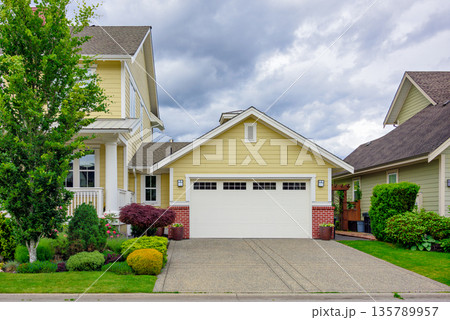 A perfect neighbourhood. Family house with wide garage door and concrete driveway in front 135789957