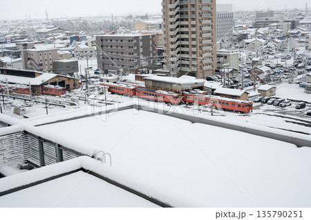 雪が積もったJR高岡駅とビルの屋上 135790251