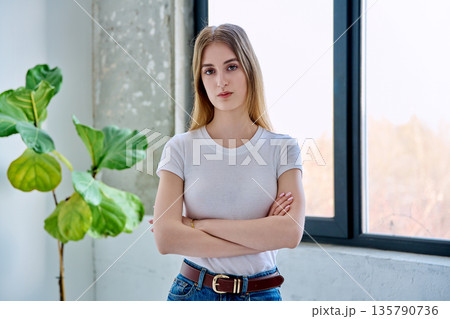Portrait of serious female teenager looking at camera with crossed arms in home Portrait of serious female teenager looking at camera with crossed arms in home 135790736