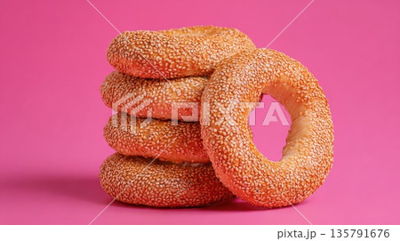 Fresh sesame seed bagels are stacked on a vibrant pink background Fresh sesame seed bagels are stacked on a vibrant pink background 135791676