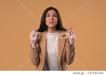Believer Businesswoman Praying, Crossed Fingers On Beige. Hope, Wish, Gratitude 135792104