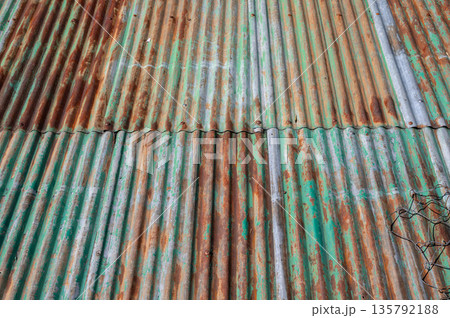 An old rusty metal sheet roof textured. Rust is an iron oxide formed by the reaction of iron and oxygen in the catalytic presence of water or air moisture. An old rusty metal sheet roof textured. Rust is an iron oxide formed by the reaction of iron and oxygen in the catalytic presence of water or air moisture. 135792188