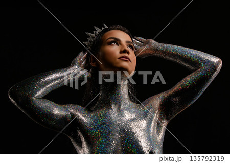 Regal woman with glitter body art and crystal crown on black background 135792319