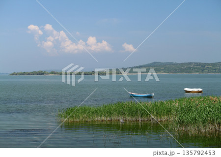 lonely fishing boat docked in calm lake. wooden fishing boat in a still lake water. image of wooden fishing boat moored on the shore. space for text. lonely fishing boat docked in calm lake. wooden fishing boat in a still lake water. image of wooden fishing boat moored on the shore. space for text. 135792453