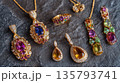 Sparkling gold jewelry with colorful gemstones rests on dark stone 135793741