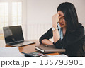 Young asian woman architect holding forehead while working on project at office desk. She is tired and tired. 135793901