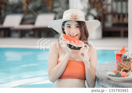 Very Beautiful woman relaxing in swimming pool and eating watermelon. Sexy young asian woman in swimsuits in summer. Very Beautiful woman relaxing in swimming pool and eating watermelon. Sexy young asian woman in swimsuits in summer. 135793981