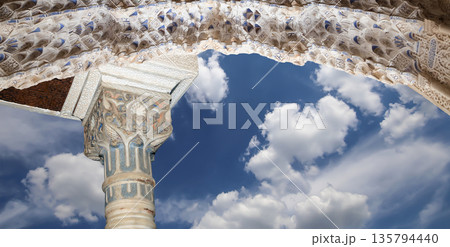 Arches in Islamic (Moorish) style (against the background of a beautiful sky with clouds) in Alhambra, Granada, Spain Arches in Islamic (Moorish) style (against the background of a beautiful sky with clouds) in Alhambra, Granada, Spain 135794440