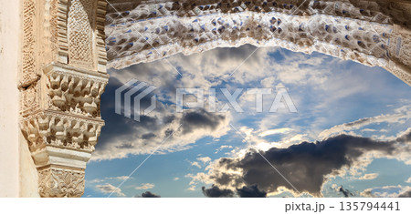 Arches in Islamic (Moorish)  style (against the background of a beautiful sky with clouds) in Alhambra, Granada, Spain 135794441