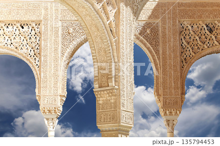 Arches in Islamic (Moorish)  style (against the background of a beautiful sky with clouds) in Alhambra, Granada, Spain 135794453