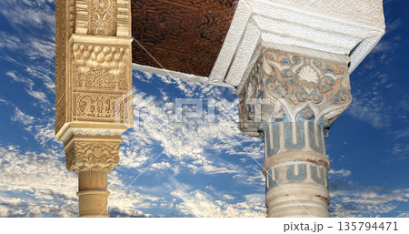 Arches in Islamic (Moorish) style (against the background of a beautiful sky with clouds) in Alhambra, Granada, Spain Arches in Islamic (Moorish) style (against the background of a beautiful sky with clouds) in Alhambra, Granada, Spain 135794471