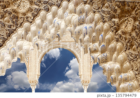 Arches in Islamic (Moorish) style (against the background of a beautiful sky with clouds) in Alhambra, Granada, Spain Arches in Islamic (Moorish) style (against the background of a beautiful sky with clouds) in Alhambra, Granada, Spain 135794479
