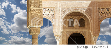 Arches in Islamic (Moorish) style (against the background of a beautiful sky with clouds) in Alhambra, Granada, Spain Arches in Islamic (Moorish) style (against the background of a beautiful sky with clouds) in Alhambra, Granada, Spain 135794491