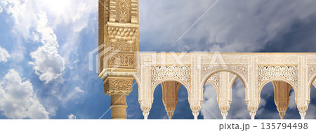 Arches in Islamic (Moorish) style (against the background of a beautiful sky with clouds) in Alhambra, Granada, Spain Arches in Islamic (Moorish) style (against the background of a beautiful sky with clouds) in Alhambra, Granada, Spain 135794498