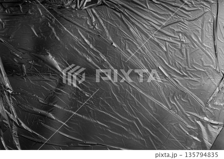 Gray plastic film texture with diagonal folds, neutral industrial background. 135794835