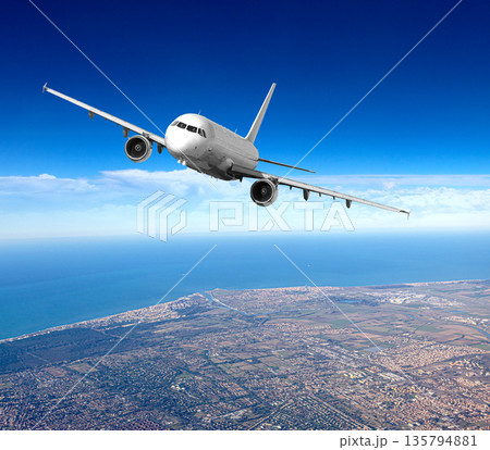Airplane flying over coastal city with sea 135794881