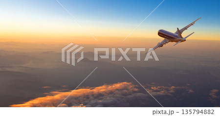 Airplane flying over mountains at sunset during golden hour Airplane flying over mountains at sunset during golden hour 135794882