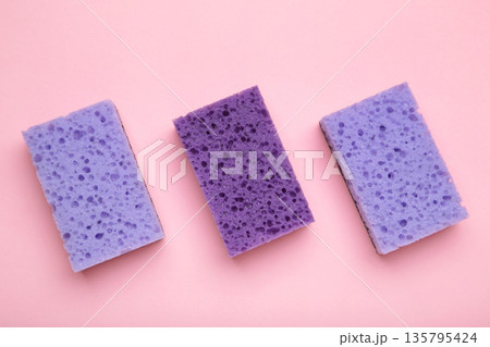 Violet dishwashing sponges on pink background. Household cleaning sponge. Violet dishwashing sponges on pink background. Household cleaning sponge. 135795424