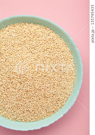 Organic white quinoa seeds in plate on pink background. Vertical photo 135795435